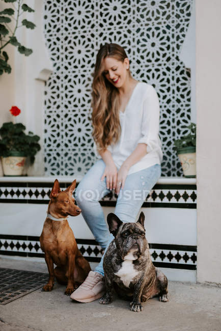 Mulher moderna na moda com bulldog e cão na rua e sorrindo — Fotografia de Stock
