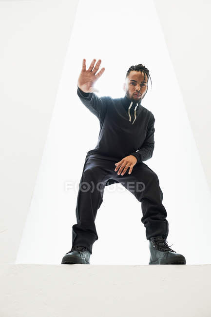 Afrikanisch-amerikanischer Mann in schwarzer Kleidung mit geflochtenen Haaren steht isoliert auf weißem Hintergrund — Stockfoto