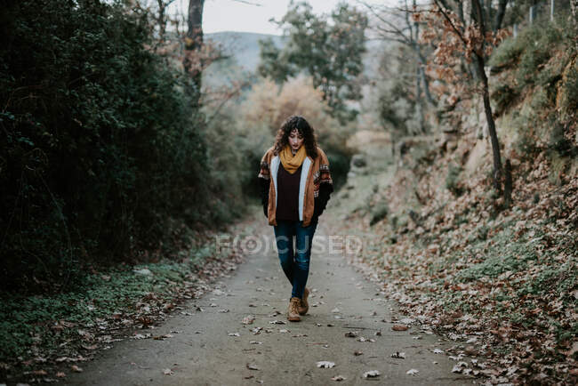 Donna attraente in giacca calda camminare nella foresta autunnale e godersi il paesaggio — Foto stock