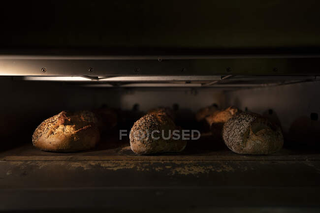 Loaves of delicious bread with crispy crust in hot oven — Stock Photo