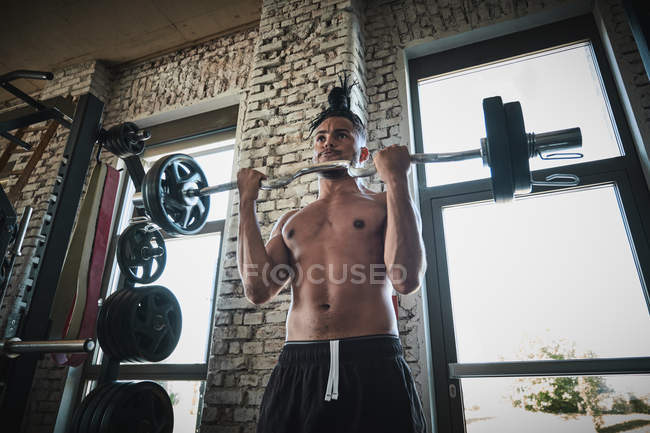 Чернокожий мужчина тренируется со штангой в тренажерном зале — стоковое фото