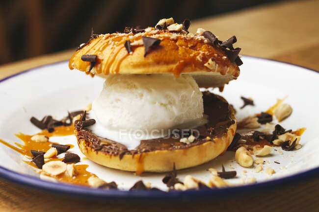 Crème glacée douce fraîche dans un hamburger au chocolat avec chapelure de noix appétissante sur une assiette blanche — Photo de stock