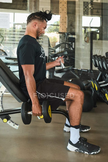 Hombre fuerte haciendo ejercicio con los pepinos en el gimnasio. - foto de stock