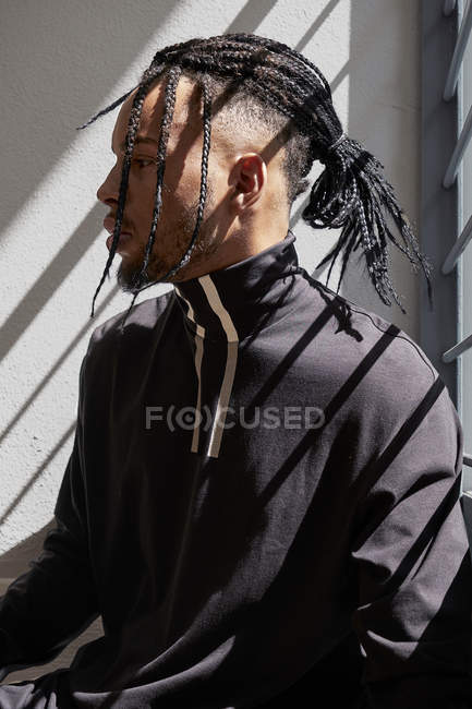 Молодой афроамериканец сидит за металлическими перилами — стоковое фото