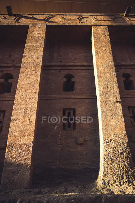 D'en bas de la belle église ancienne taillée dans la roche extérieure avec des fenêtres sculptées et des croix en pierre, Ethiopie — Photo de stock