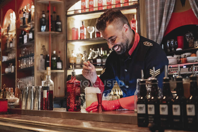 Lächelnder Barmann in Uniform und rotem Handschuh bereitet Rauchcocktail zu — Stockfoto