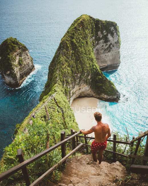 Man on viewpoint above tropical seashore with cliffs — Stock Photo