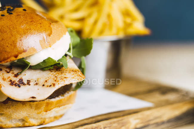 Juicy delicious burger and fried potato on wooden table — Stock Photo