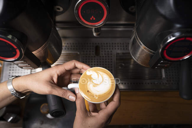 Растениеводство рук человека, делающего кофе с помощью автоматического профессионального оборудования в кафе — стоковое фото
