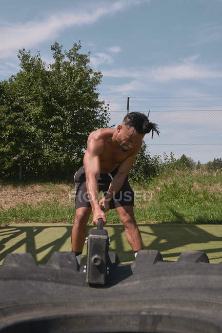Musculoso negro chico martilleo neumático en el gimnasio al aire libre - foto de stock
