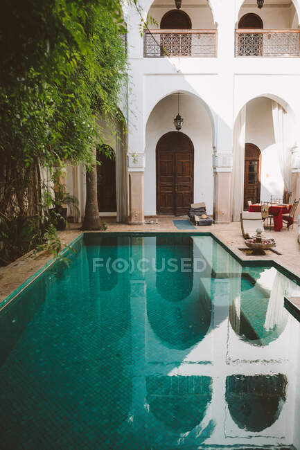 Peaceful clear water of pool on terrace of exotic resort with oriental architecture in sunlight, Morocco — Stock Photo
