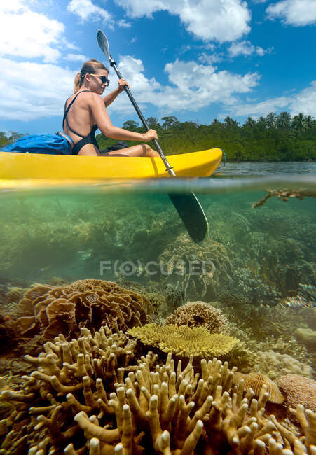 Sportive woman traveling on canoe in tropical lagoon — Stock Photo