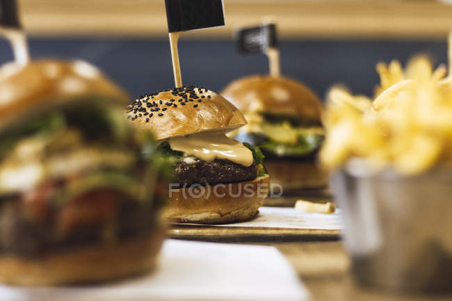 Juicy delicious burgers and fried potato on wooden table — Stock Photo