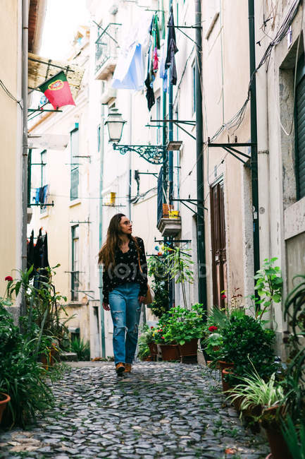 Young casual brunette walking on cobblestone street of old city — Stock Photo