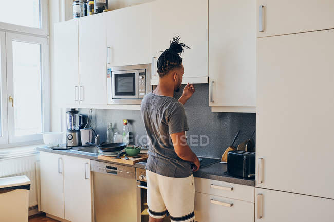 Uomo afroamericano intrecciato in piedi in cucina e cucina — Foto stock