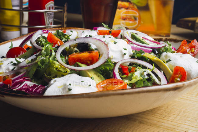 Ensalada de verduras con verduras de cebolla y salsa de crema servida en el plato - foto de stock