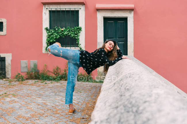 Young slim casual woman stretching on street of old city while dancing gracefully — Stock Photo