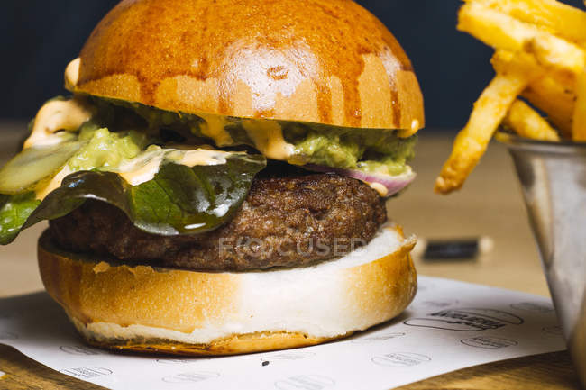 Closeup of juicy delicious burger and fried potato on table — Stock Photo