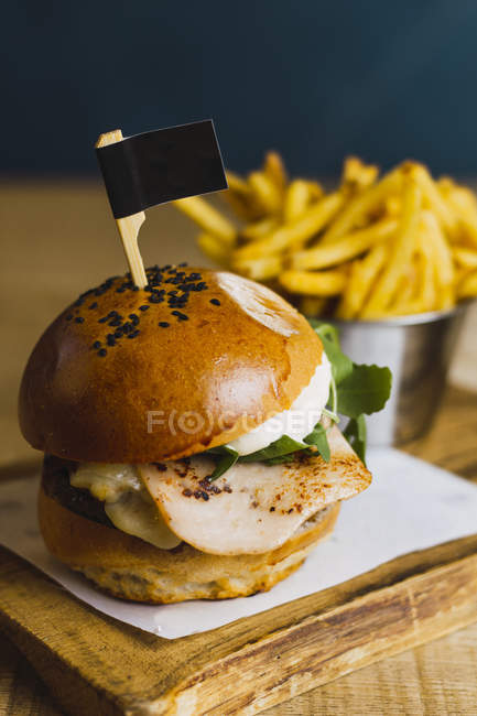 Juicy delicious burger and fried potato on wooden table — Stock Photo