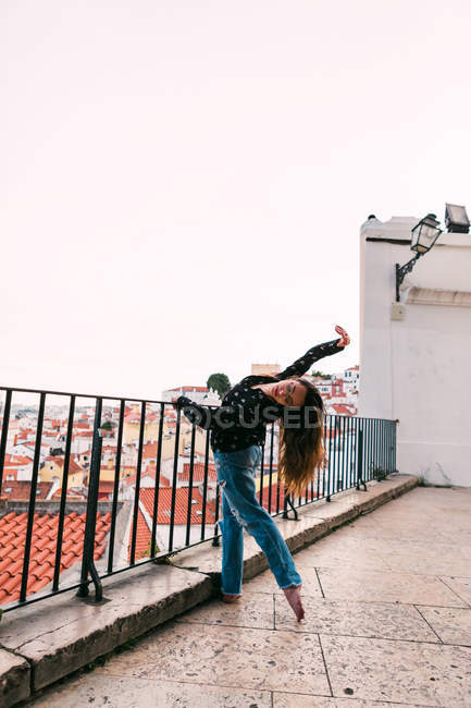 Випадкова молода жінка танцює на фоні прибережного міста — стокове фото