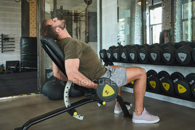 Strong man exercising with dumbbells in gym — Stock Photo