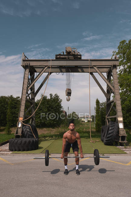 Chico negro con barra en gimnasio al aire libre - foto de stock