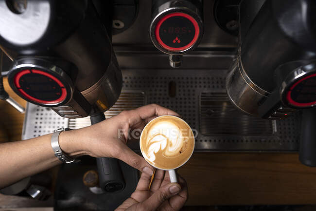 Las manos de la cosecha del hombre haciendo café por el equipo profesional automático en la cafetería - foto de stock