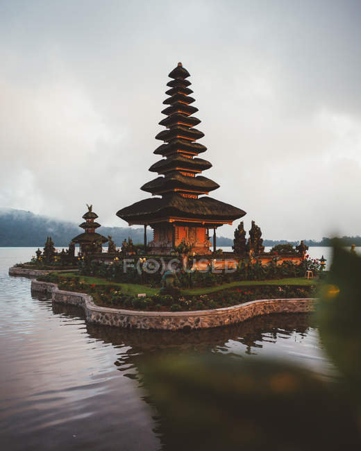 Petit complexe de pagode de prière avec jardin verdoyant autour construit dans l'eau sur le rivage contre le brouillard, Bali — Photo de stock