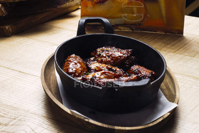De haut appétissante viande frite aromatique saupoudrée de verts dans une casserole épaisse en fonte profonde — Photo de stock