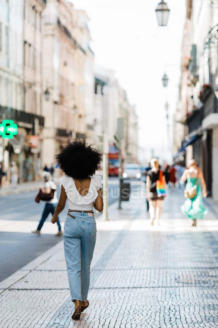 Visão traseira da mulher étnica na roupa da moda andando no dia de verão — Fotografia de Stock