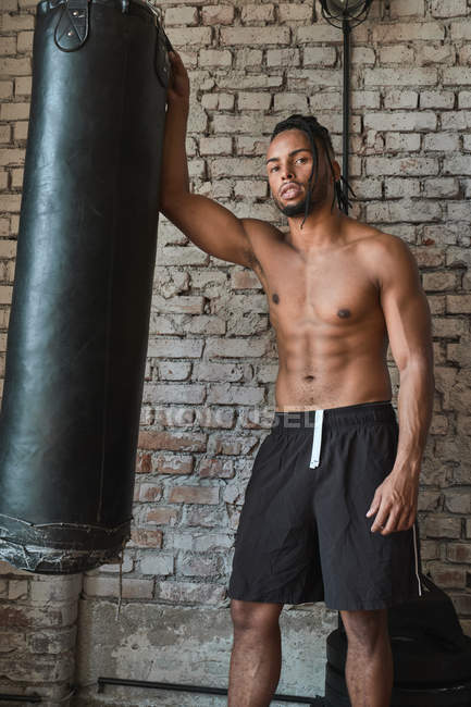 Boxeador negro de confianza en el gimnasio con bolsa de boxeo. - foto de stock