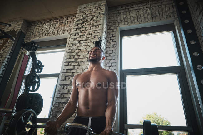Чернокожий мужчина тренируется со штангой в тренажерном зале — стоковое фото