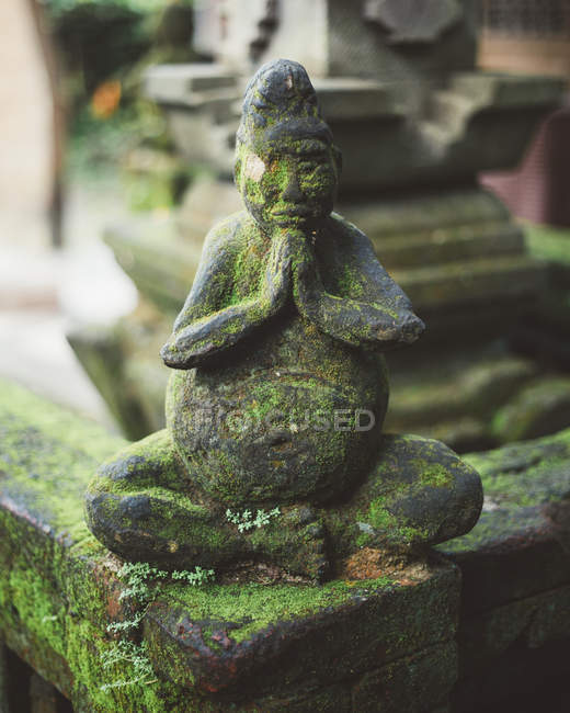 Recinzione in pietra con statua del monaco orante ricoperta di muschio — Foto stock