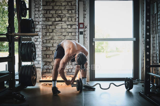 Строгий мускулистый мужчина занимается со штангой в тренажерном зале — стоковое фото