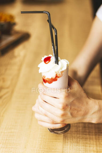 Белое мороженое в бумажном конусе в руках — стоковое фото