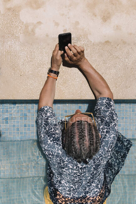 Старший чоловік використовує смартфон у басейні — стокове фото