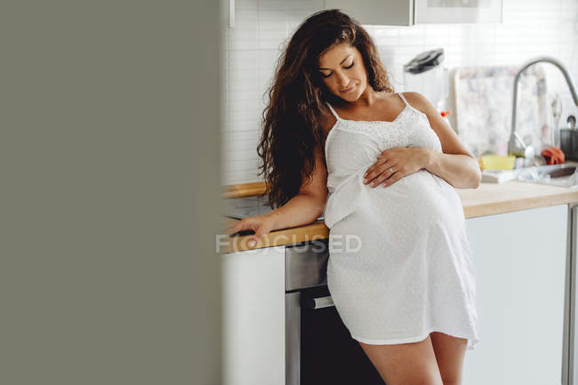Счастливая беременная женщина стоит на кухне — стоковое фото