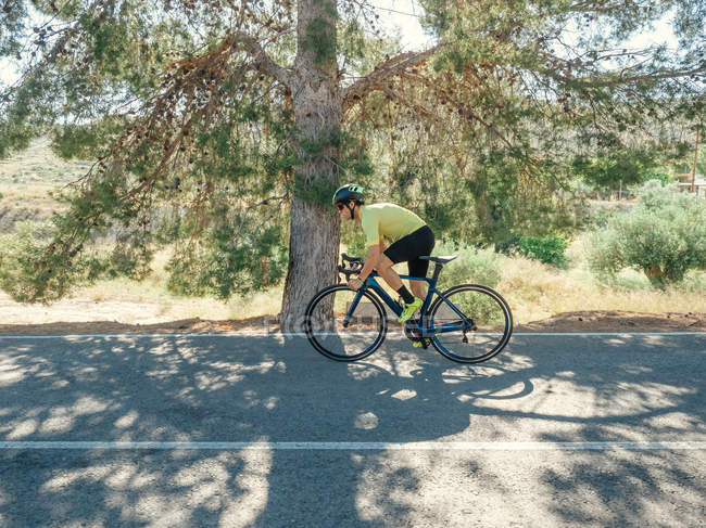 Здоровий чоловік їде на велосипеді на гірській дорозі в сонячний день — стокове фото