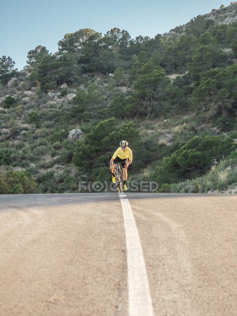 Здоровый человек на велосипеде по горной дороге в солнечный день — стоковое фото