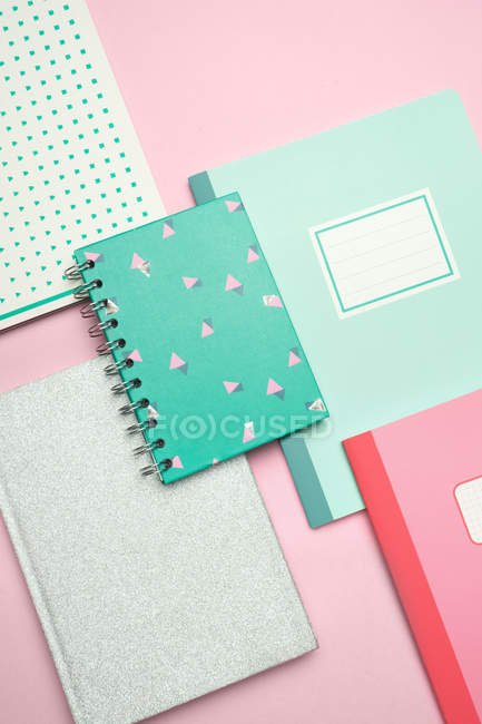 Komposition aus bunten Notizbüchern auf rosa Schreibtisch angeordnet — Stockfoto