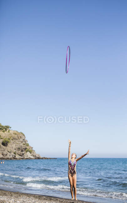 Graceful acrobat performs with hoop on beach — Stock Photo