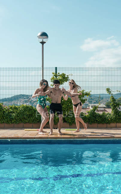 Amici che giocano in piscina in una soleggiata giornata estiva — Foto stock