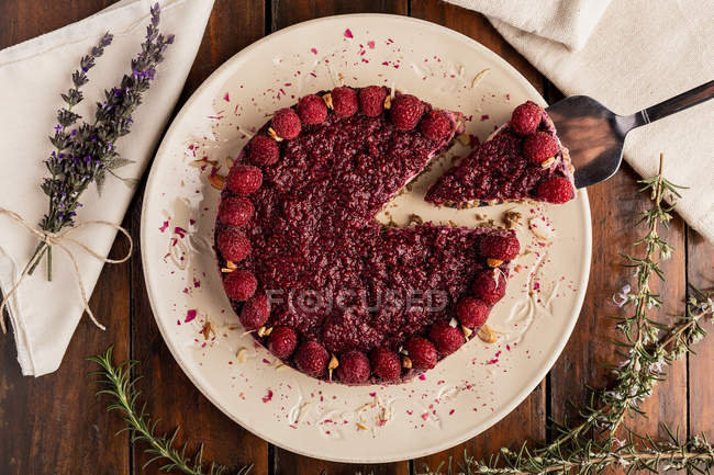 Gâteau aux fruits juteux tranché aux framboises sur plaque blanche sur table en bois décorée d'un bouquet de lavande — Photo de stock