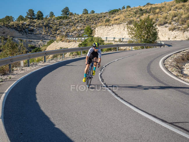 Homem saudável andar de bicicleta na estrada da montanha em dia ensolarado — Fotografia de Stock