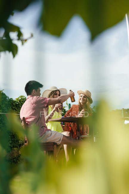 Група друзів п'ють пиво на терасі бару в сонячний день — стокове фото