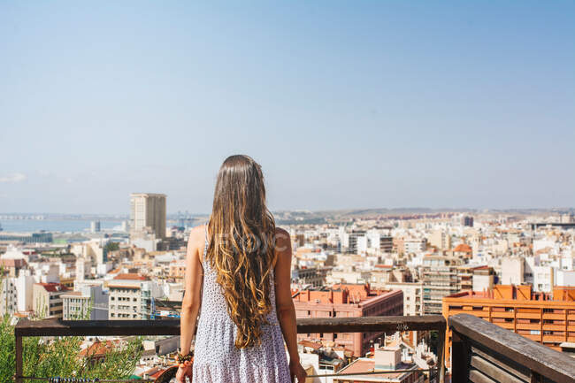 Woman on balcony looking at city views from above — Stock Photo