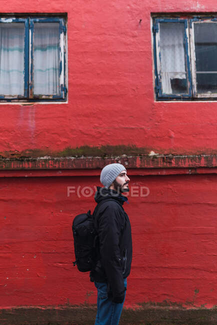 Bärtiger Mann schaut weg, während er vor rotem Gebäude auf Färöer-Insel steht — Stockfoto