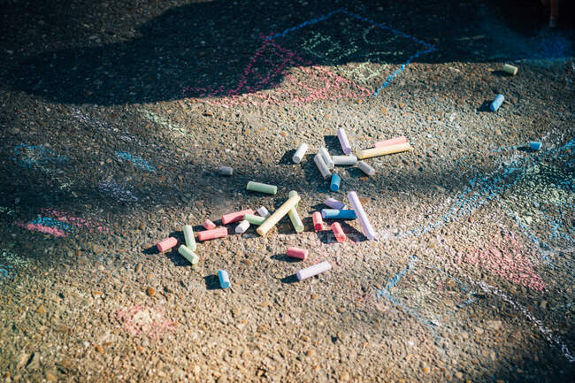 Dall'alto rosso blu verde viola gesso e bambini disegni su asfalto nella giornata di sole — Foto stock