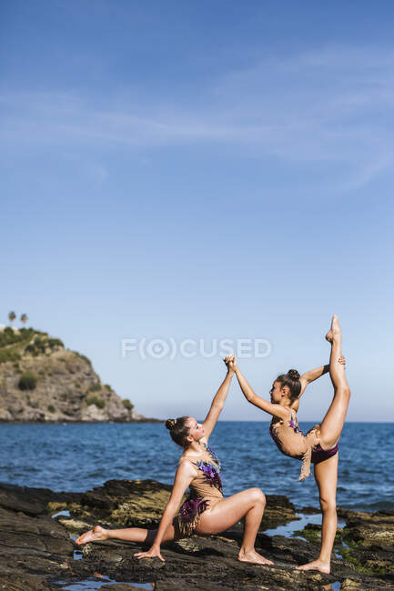 Elegantes gimnastas entrenando en rocas - foto de stock