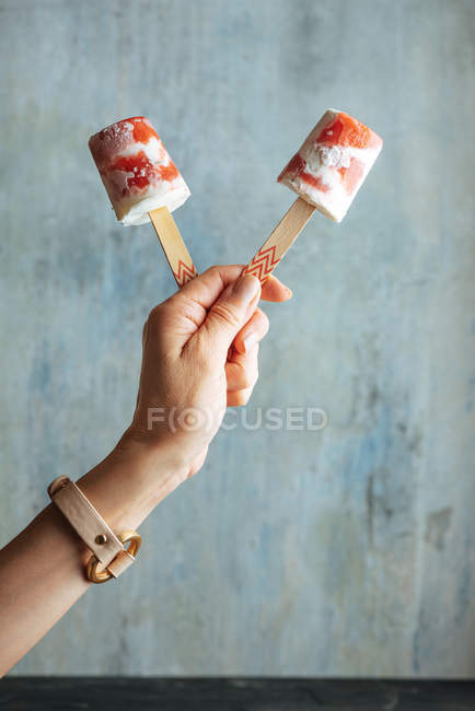 Main féminine tenant pastèque et crème glacée sur fond bleu clair — Photo de stock